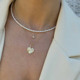 Close-up of a person layering  three necklaces with north star and heart pendants on a neutral background. with a  seed pearl necklace