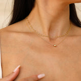 Close-up of a person wearing two gold -filled layering necklaces.