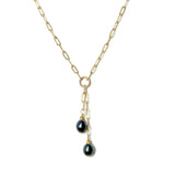 Gold lariat with peacock pearl dangles on a white background