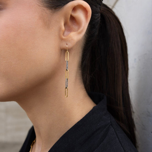 Close-up of a person wearing gold earrings with a neutral background